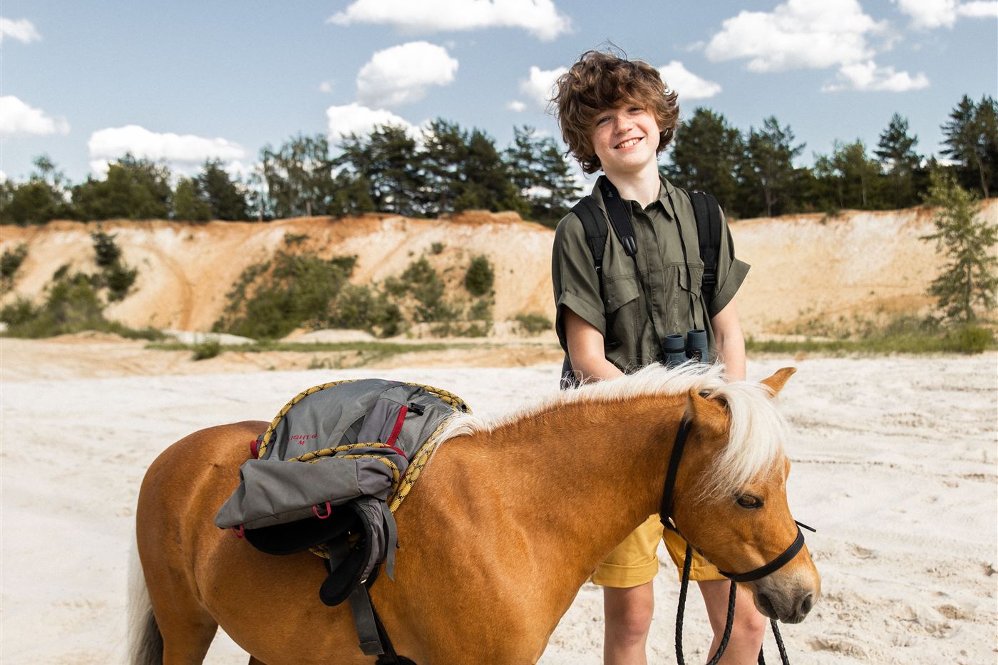Un enfant souriant à côté de son poney